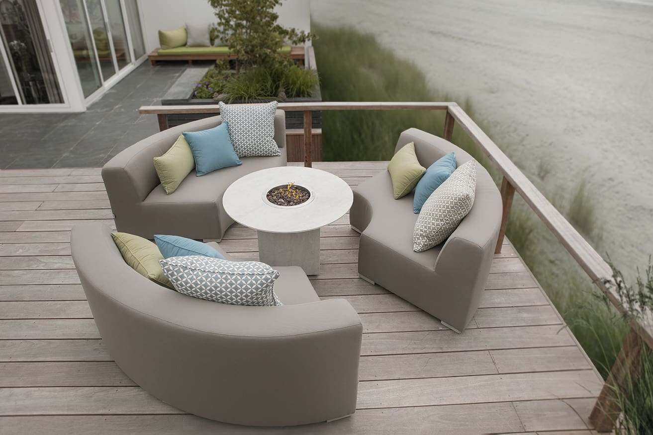 Ronde all weather loungeset in taupe rond een vuurtafel op een houten terras