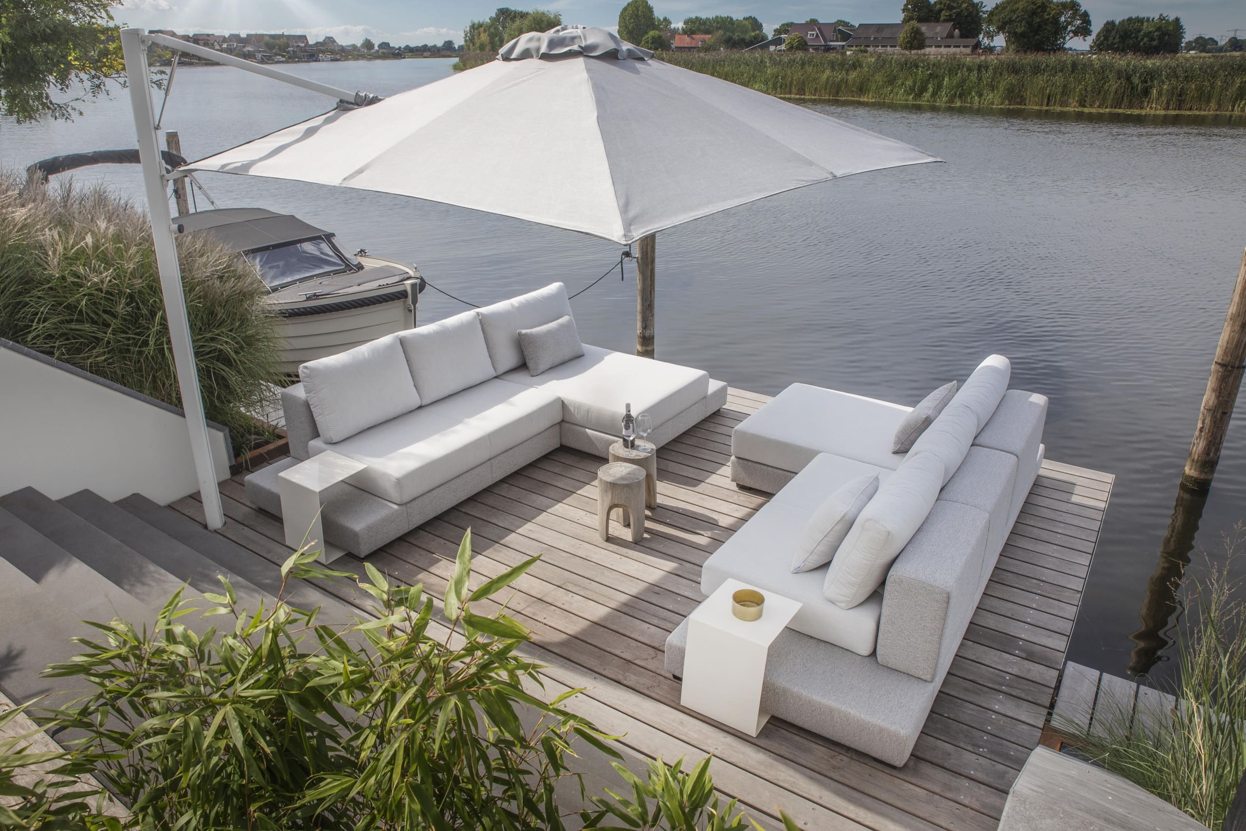 All weather loungeset met parasol op een houten vlonder aan het water
