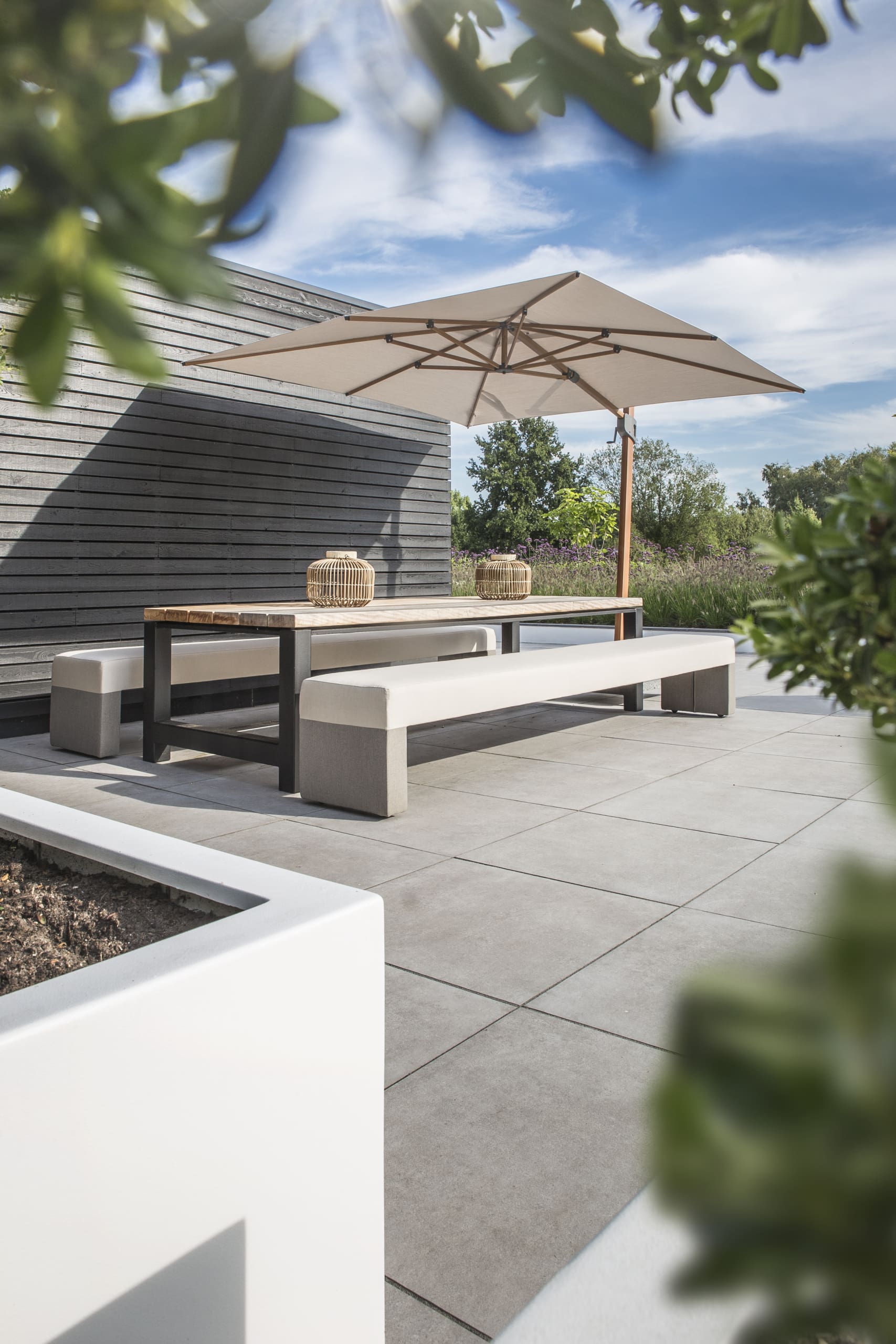 Tuintafel op maat met banken en parasol op een terras