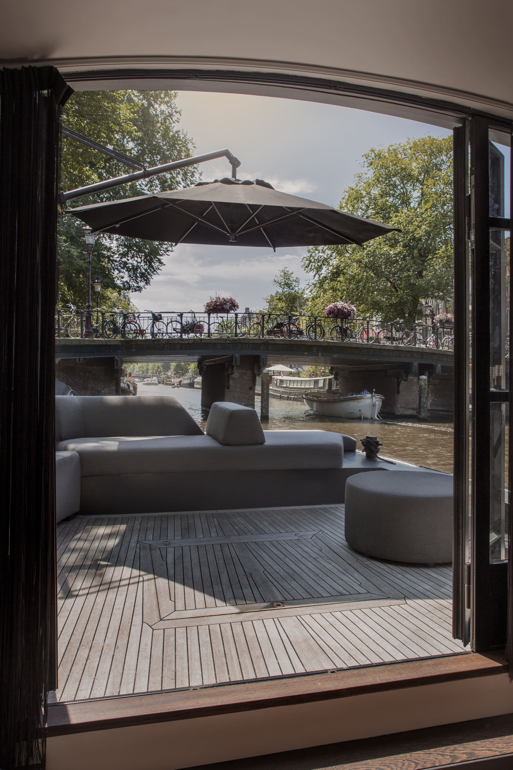 Loungeset op een terras aan de gracht, gezien door openslaande deuren